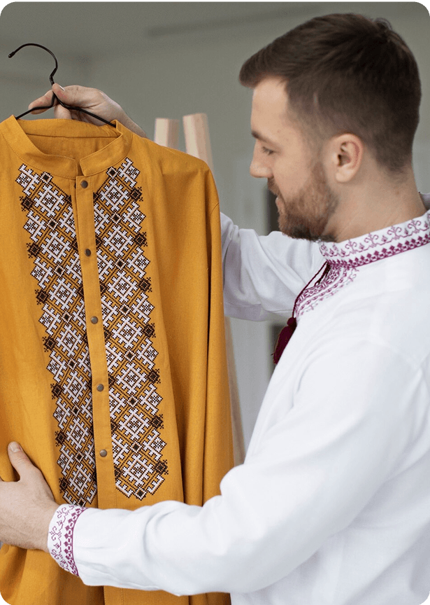 A man holding up and admiring traditional muslim clothing