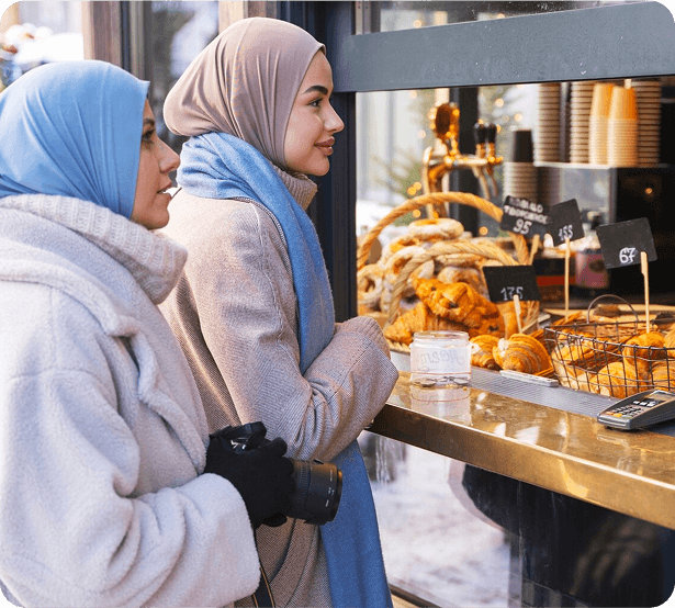 Two women wearing hijab ordering fruit from a stall