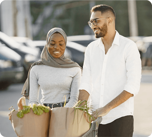 A muslim couple walking to their car carrying groceries